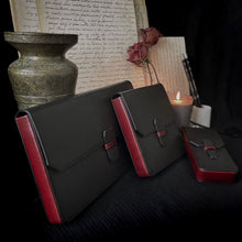 Load image into Gallery viewer, Three Franklin-Christoph New Penvelope 12 Black Merlot Leather cases sit before vintage letters, brass, and dried roses.