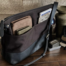 Load image into Gallery viewer, The Fortis Sling Bag by Franklin-Christoph holds essentials on a table beside tins. Water repellent, with outer pockets.