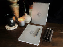 Load image into Gallery viewer, Greybooks by Franklin-Christoph, A5 refills, a pen case, candle, and decor create a cozy workspace on a wood table.