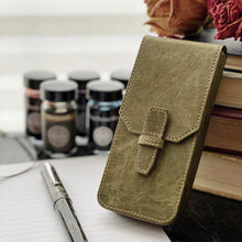 Load image into Gallery viewer, Franklin-Christoph New Penvelope 3 NWF in olive green with removable slots; ink bottles, books in the background.
