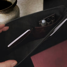 Load image into Gallery viewer, A hand opens a Franklin-Christoph Gear Bag, revealing notebooks, pens, and nearby are a metallic vase and red item.