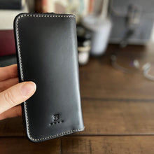 Load image into Gallery viewer, A hand holds the Franklin-Christoph 4 Nib Case, a black leather case with white stitching for fountain pen nib storage.