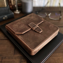 Load image into Gallery viewer, The Franklin-Christoph New Penvelope 6 Boot Brown Leather sits atop a closed black notebook on a wooden desk.
