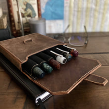 Load image into Gallery viewer, A Franklin-Christoph New Penvelope 6 Boot Brown Leather case holds pens on a desk with a notebook, glasses, and art.