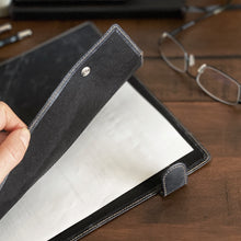 Load image into Gallery viewer, A hand opens a Franklin-Christoph Document Folder - NWF Colors on a natural wood desk, with A4 papers and eyeglasses.