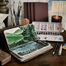 Load image into Gallery viewer, A watercolor landscape on Franklin-Christoph Water Color Paper - VN Refill, with art supplies on a wooden desk.